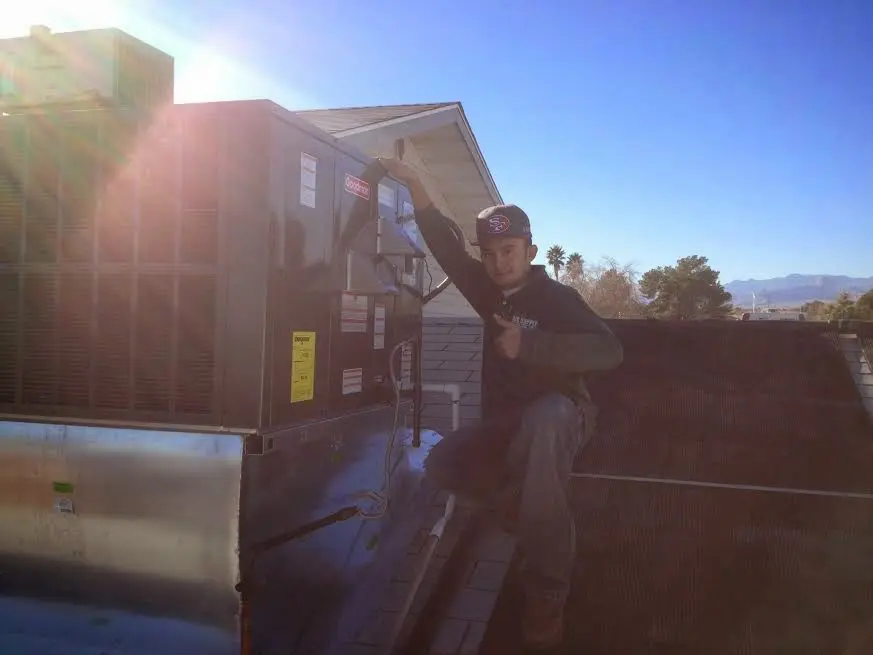 HVAC technician performing Boiler Repair on a rooftop unit in Fowler