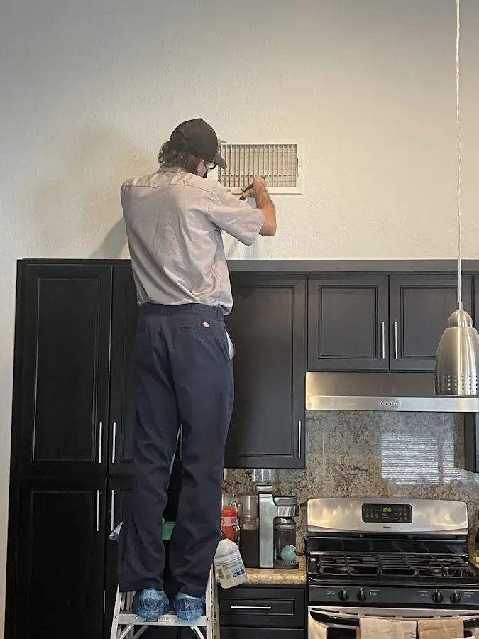 Technician inspecting an air vent during HVAC service in Fowler